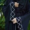 Elegant black abaya with white geometric embroidery, perfect for modest fashion and everyday wear.