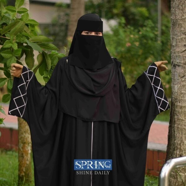 1. Female in black Islamic abaya and niqab outdoors, greenery background, modest fashion.
